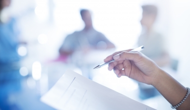 Close up businesswoman holding pen reviewing paperwork